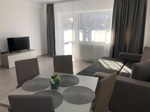 ein Wohnzimmer mit Sofa, Tisch und Stühlen in der Unterkunft Elena-Maria Apartments in Buşteni