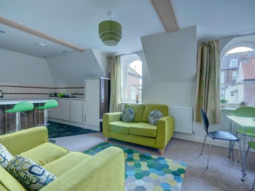 uma sala de estar com um sofá verde e uma cozinha em The Old Auction Rooms em Whitby