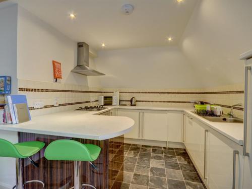 a kitchen with white cabinets and green bar stools at The Old Auction Rooms Lot 2 Central with Private Parking in Whitby