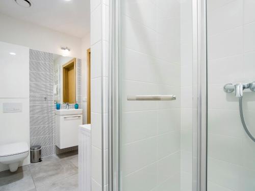 a white bathroom with a shower and a toilet at Riverside Aparthotel Cracow in Kraków