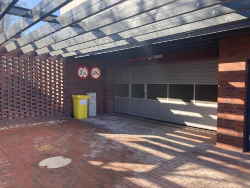 a building with a garage with awning and a yellow trash can at JAB Apartament Przy Klinice Business & Family in Szczecin