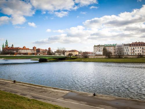 a bridge over a river with buildings in the background at Riverside Aparthotel Cracow in Kraków
