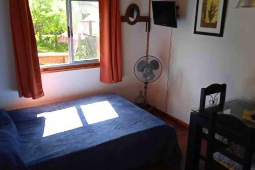 a bedroom with a bed and a window and a fan at • Cabaña Las Hortensias • in La Pedrera