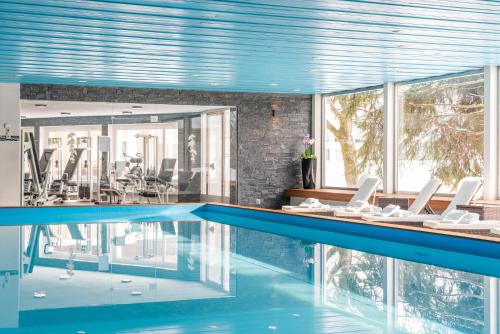 a swimming pool with chairs in a house at Hotel Europe in Davos