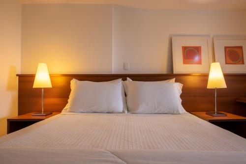 a bedroom with a large bed with two lamps at Hotel Habitare in Nova Friburgo