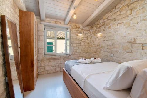 1 dormitorio con 2 camas y pared de piedra en Lakka Stone House 1, en Gáios
