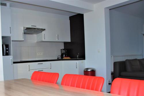 a kitchen with two orange chairs and a table at Juwel Fruithof in Zepperen