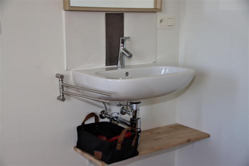 a sink in a bathroom with a bag underneath it at Juwel Fruithof in Zepperen