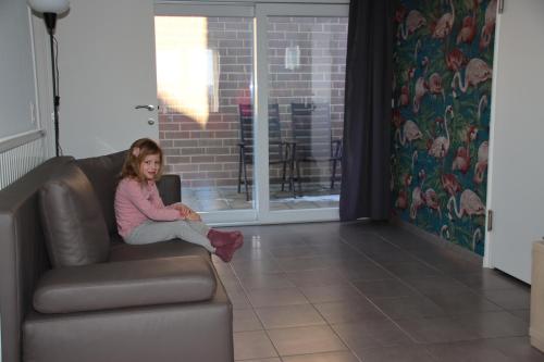 a girl sitting on a couch in a living room at Juwel Fruithof in Zepperen