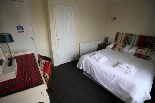 a bedroom with a bed with white sheets and a table at The White Hart in Whitchurch