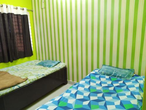 two beds in a room with green and white stripes at Nand Villa 2Bhk in Bharbharia