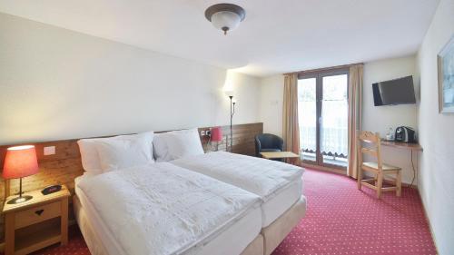 a hotel room with a bed and a desk and a window at Le Chamois in Les Diablerets