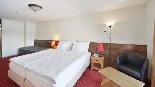 a hotel room with a bed and a chair at Le Chamois in Les Diablerets