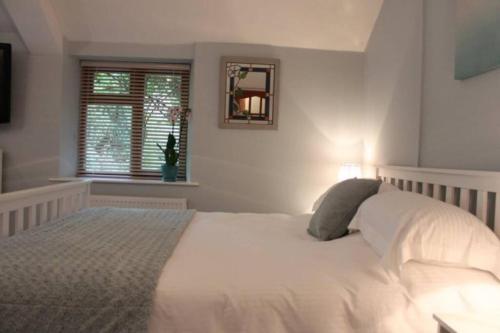 a bedroom with a white bed and a window at The Little Acorn in Lydney