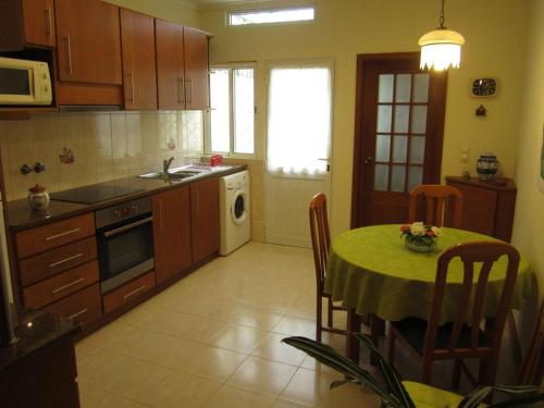 eine Küche mit einem Tisch und einem grünen Tischtuch in der Unterkunft Casa Nuno e Lorena - Casa completa e Localização ideal in Ponta Delgada