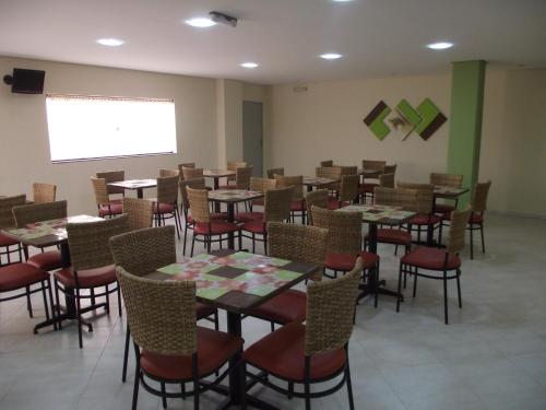 a dining room with tables and chairs and a screen at Hotel Eden in Sorocaba
