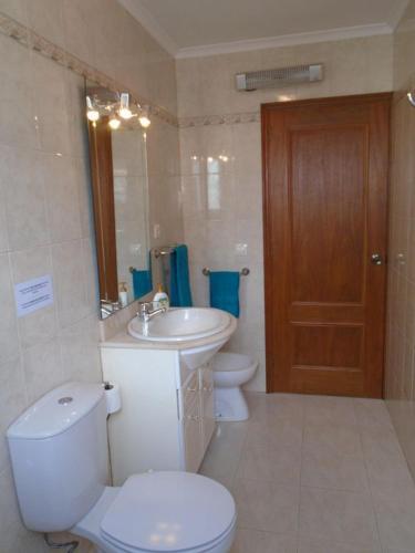 a bathroom with a toilet and a sink and a mirror at Casa Nuno e Lorena - Casa completa e Localização ideal in Ponta Delgada