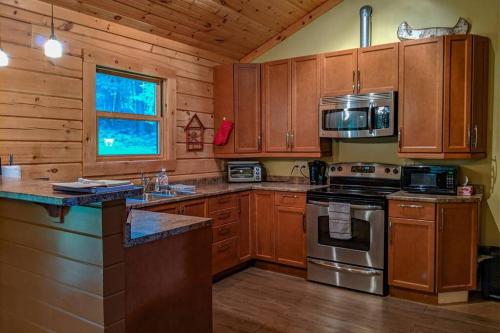 a kitchen with wooden cabinets and a stove top oven at Chalet Le Boisé in Wakefield