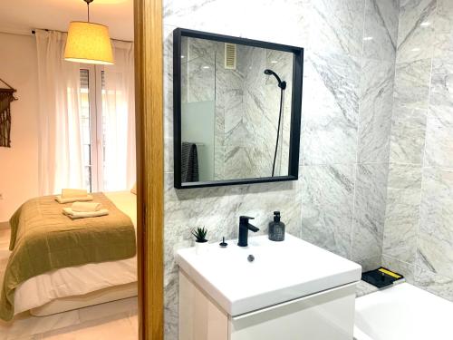 un bagno con lavandino, specchio e letto di Homely Málaga Larios a Málaga