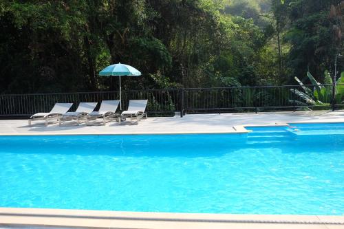 a group of chairs and an umbrella next to a swimming pool at Namtok Sarika Resotel in Nakhon Nayok