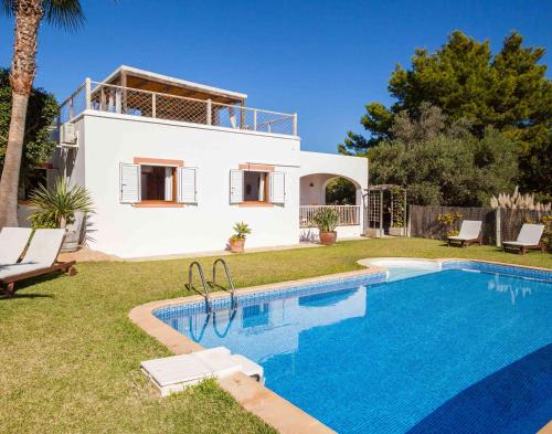 a villa with a swimming pool in front of a house at Villa Es Cubells 204 in Es Cubells