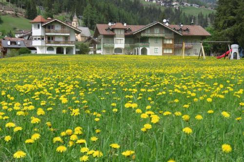 a field of yellow flowers in front of a house at Residence Holiday in Pozza di Fassa