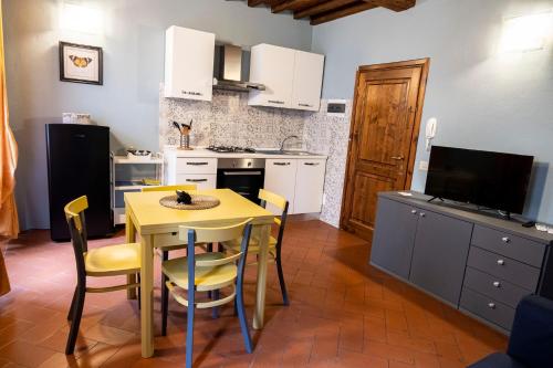 eine Küche mit einem gelben Tisch und Stühlen sowie einem TV in der Unterkunft Residenza Roma in Pistoia