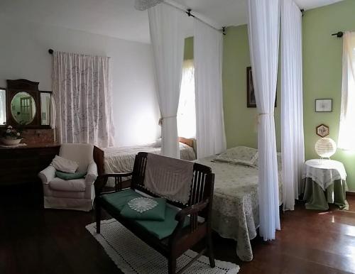 a bedroom with a bed and a chair and a window at Refúgio Pasárgada Guest House in Mairiporã
