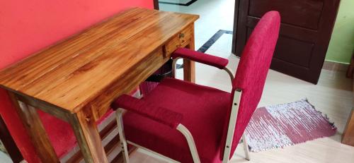 a wooden desk with a red chair next to a table at SEVENSTAR RESIDENCY in Varkala