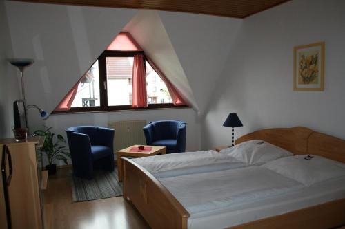 1 Schlafzimmer mit einem Bett, 2 Stühlen und einem Fenster in der Unterkunft Kurpark-Residenz Deidesheim in Deidesheim