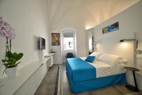 a white bedroom with a blue bed and a window at Sunshine Luxury Rooms in Ostuni