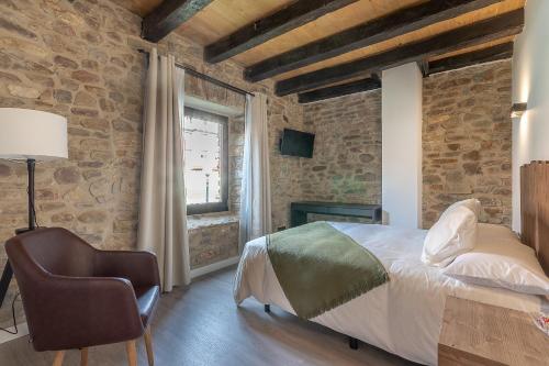 a bedroom with brick walls and a bed and a chair at Burruzkale Etxea in Murueta-Orozko