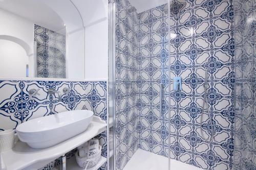 uma casa de banho com paredes em azulejos azuis e brancos e um chuveiro em Maison Don Rafe' em Positano