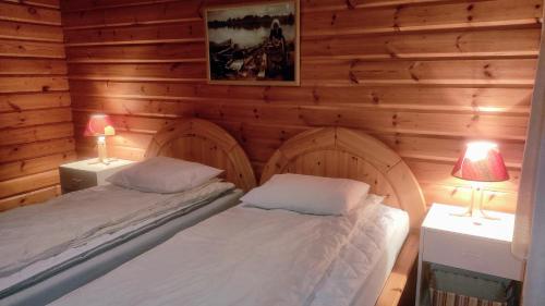 Habitación de madera con 2 camas y 2 lámparas en Holiday Cabin Kerimaa 102 en Savonlinna