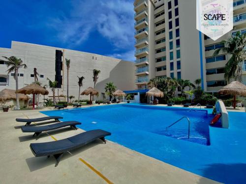 a swimming pool with chairs and a building at Residencial Salvia in Cancún