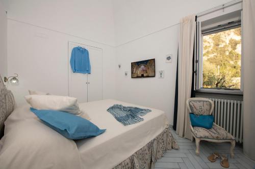 a bedroom with a bed with blue pillows and a chair at Maison Don Rafe' in Positano