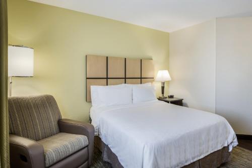 a hotel room with a large bed and a chair at Candlewood Suites Virginia Beach Town Center by IHG in Virginia Beach