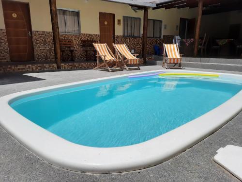 une grande piscine avec deux chaises en face d'un bâtiment dans l'établissement Pousada Pelourinho, à Mucuri