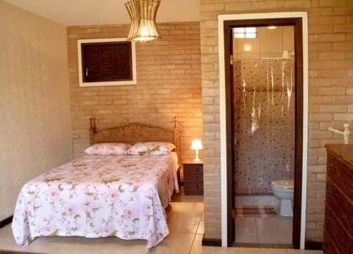 a bedroom with a bed and a bathroom with a shower at Pousada Cantinho das Fadas in Conceição da Ibitipoca