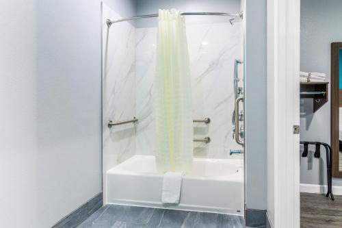 a bathroom with a shower with a white tub at Americas Best Value Inn & Suites Kingwood IAH Airport in Kingwood