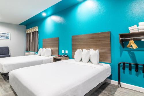 two beds in a hotel room with blue walls at Americas Best Value Inn & Suites Kingwood IAH Airport in Kingwood