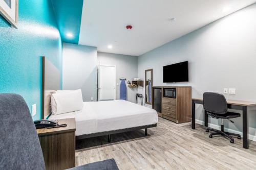 a hotel room with a bed and a desk and a tv at Scottish Inns & Suites - Kingwood in Kingwood