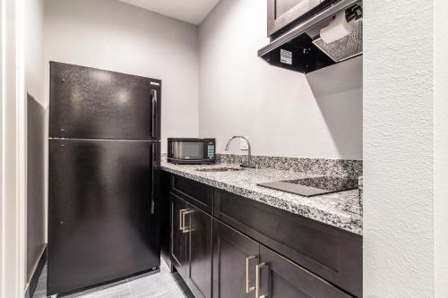 a kitchen with a refrigerator and a sink at Scottish Inns & Suites - Kingwood in Kingwood