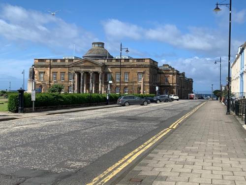 a building on a street with cars parked in front of it at Ayr Loft Apartment with Fabulous Views in Ayr