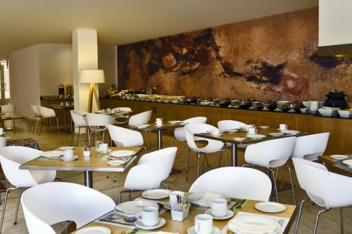 a dining room with tables and white chairs at Fiesta Inn Leon in León