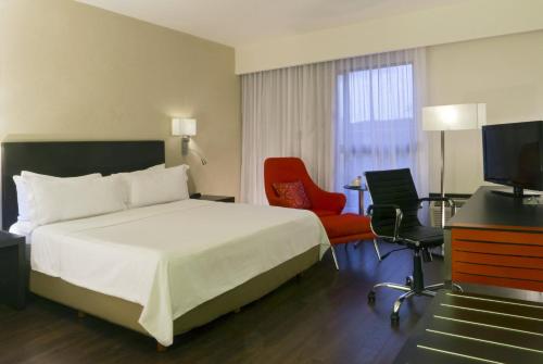 レオンにあるフィエスタ イン レオンのベッド、デスク、テレビが備わるホテルルームです。