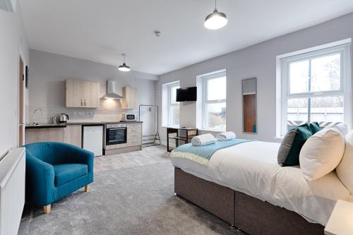 a bedroom with a large bed and a blue chair at Copper House- Smart Stay near Stadium & City in Swansea