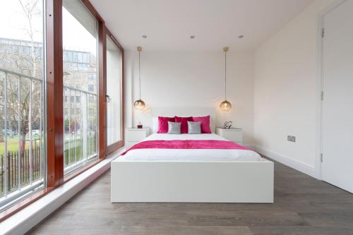 una camera da letto con un grande letto bianco e ampie finestre di City Living apartments a Londra