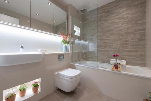 a bathroom with a toilet and a sink and a tub at City Living apartments in London
