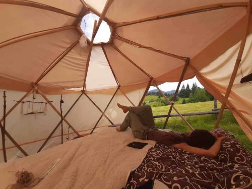 a person laying on a bed in a tent at Eco glamping - Carpathians. Retreat hub Dzin Space in Verkhovyna